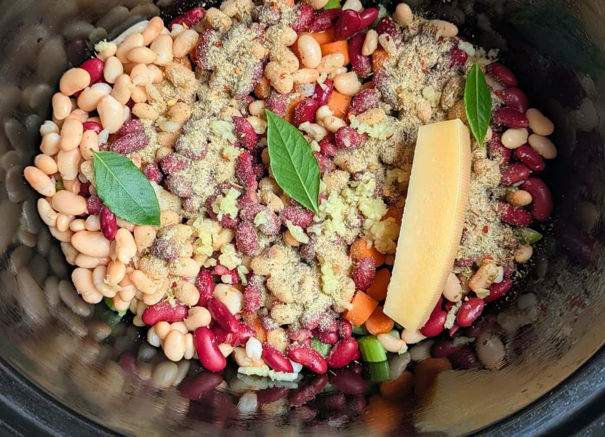 beans, carrots, celery, seassoning, garlic, bay leaves, parmesan rind added to the slow cooker