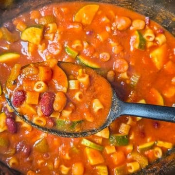 ladle scooping up a hearty serving of minestrone soup from the slow cooker
