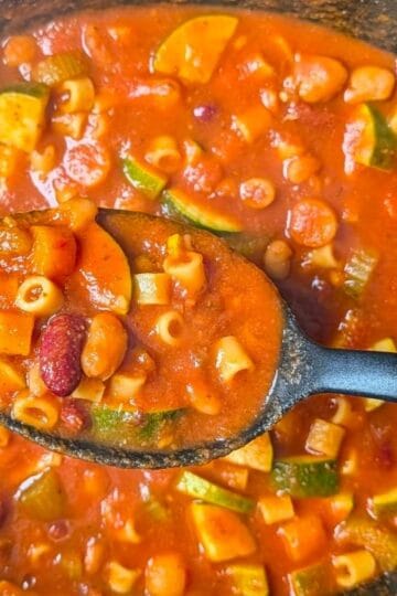 ladle scooping up a hearty serving of minestrone soup from the slow cooker